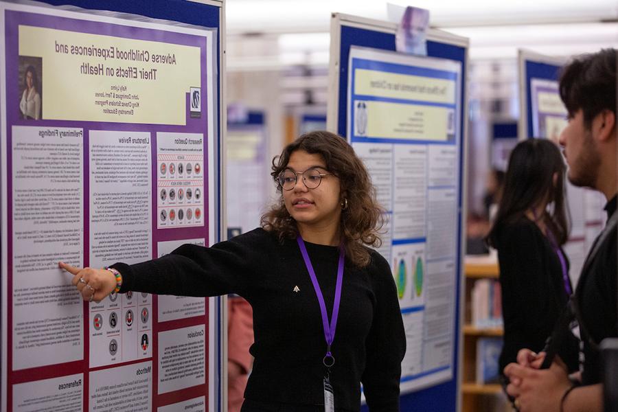 A student shares their research on a large board.