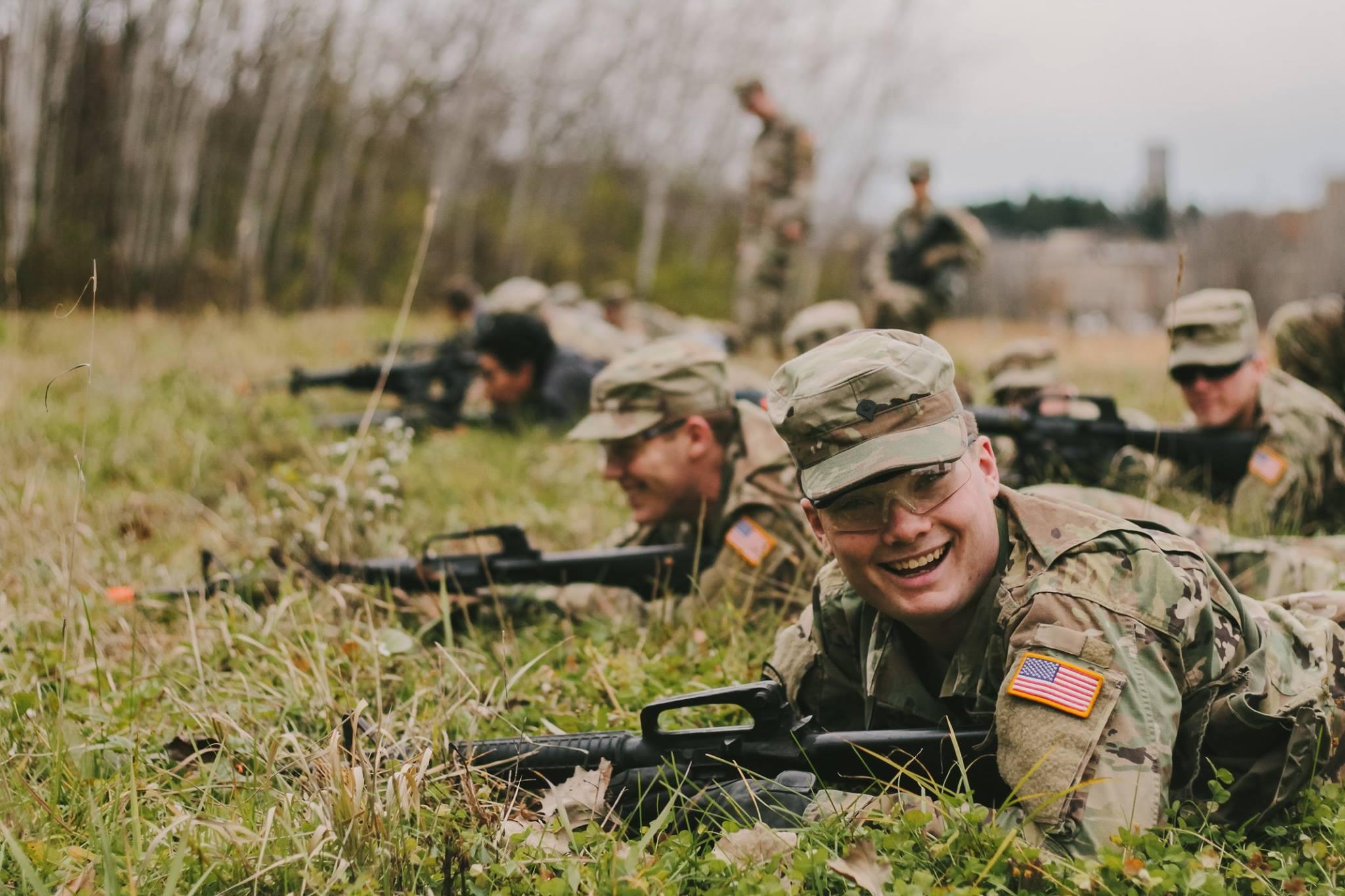 students in uniform smiling while crawling through a field