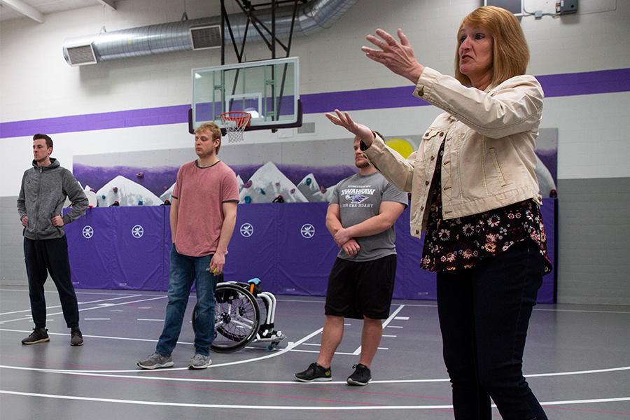 Kathleen Happel speaks with students in a gym.