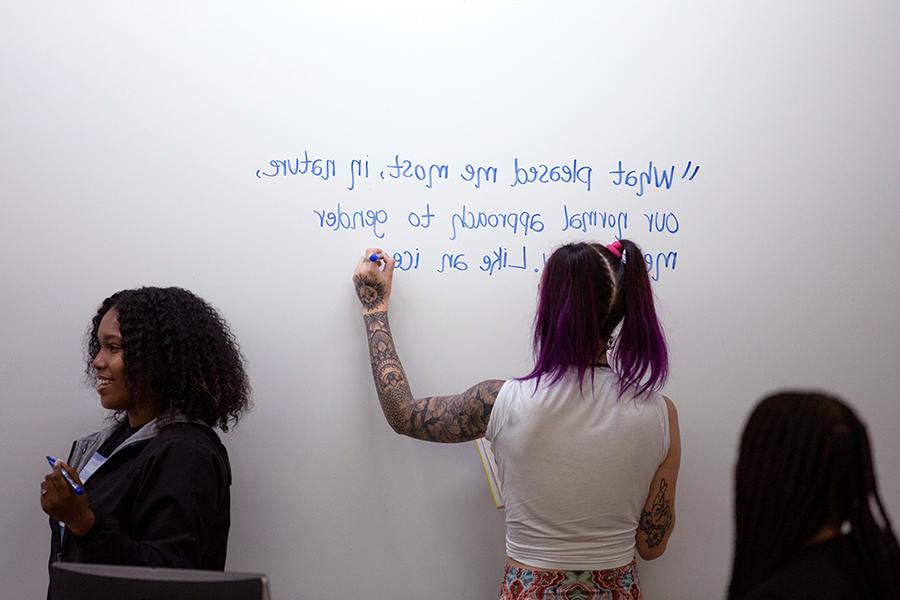 Students in Sevick’s class prepare to welcome author and producer Jacob Tobia to a memoir-writing class by writing quotes by Tobia on the whiteboard.