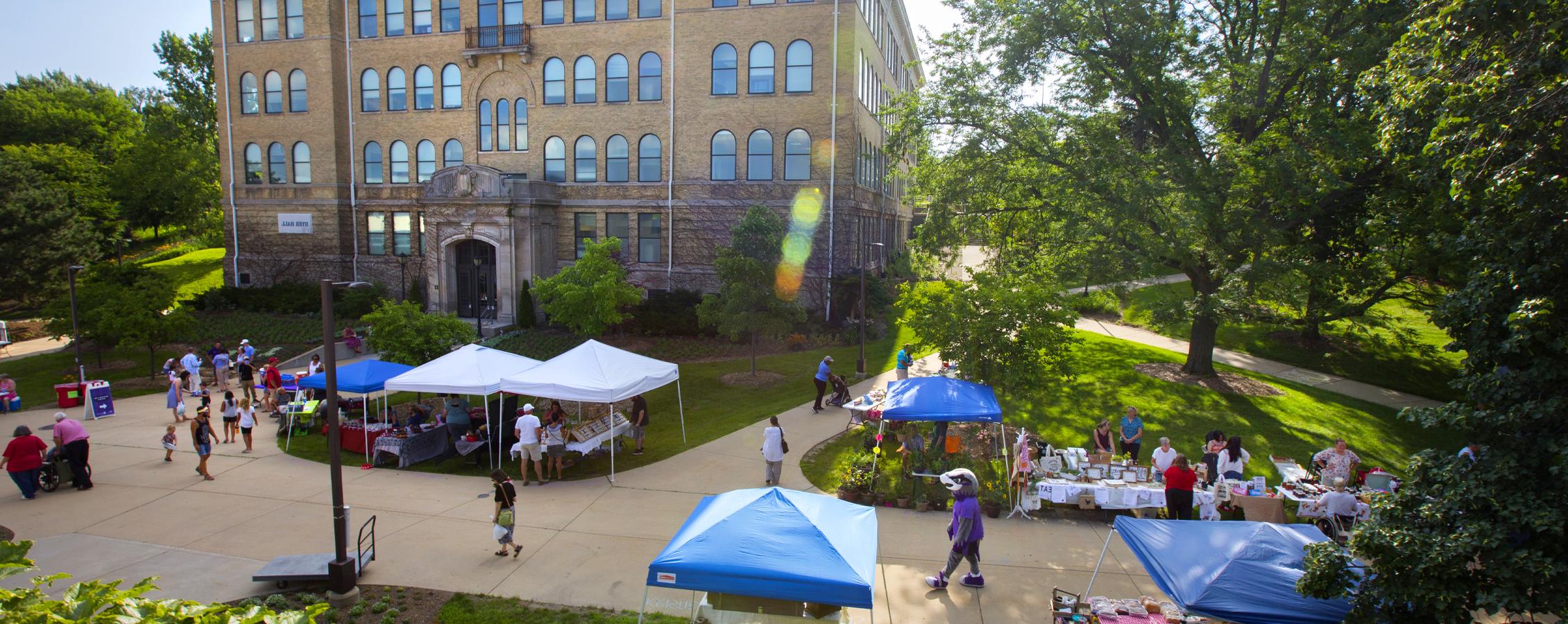 Exterior shot of Hyer Hall: Willie Warhawk and pop tents fill the sidewalk in front of the building.